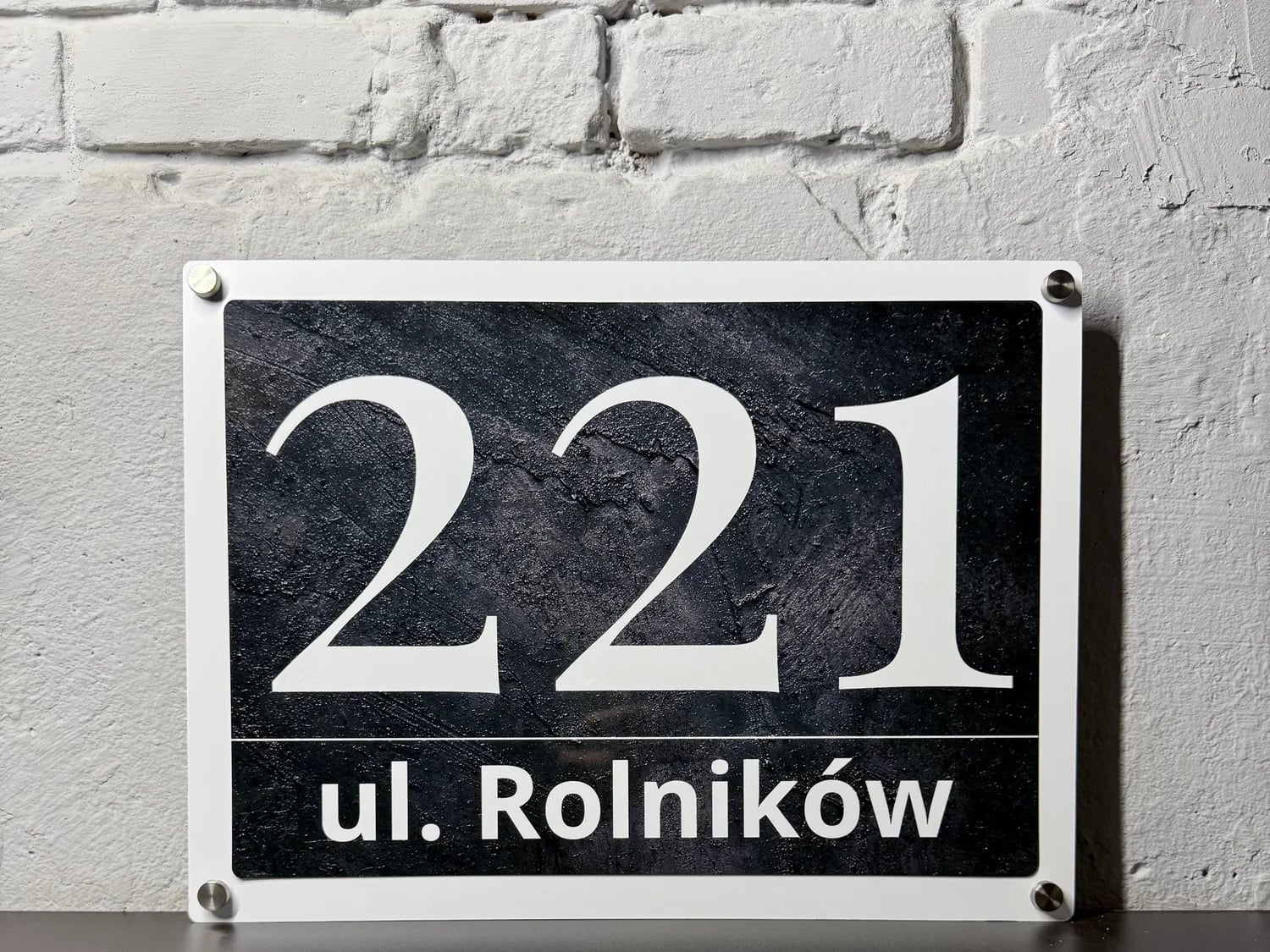 Glossy metal address sign mounted on a modern house wall