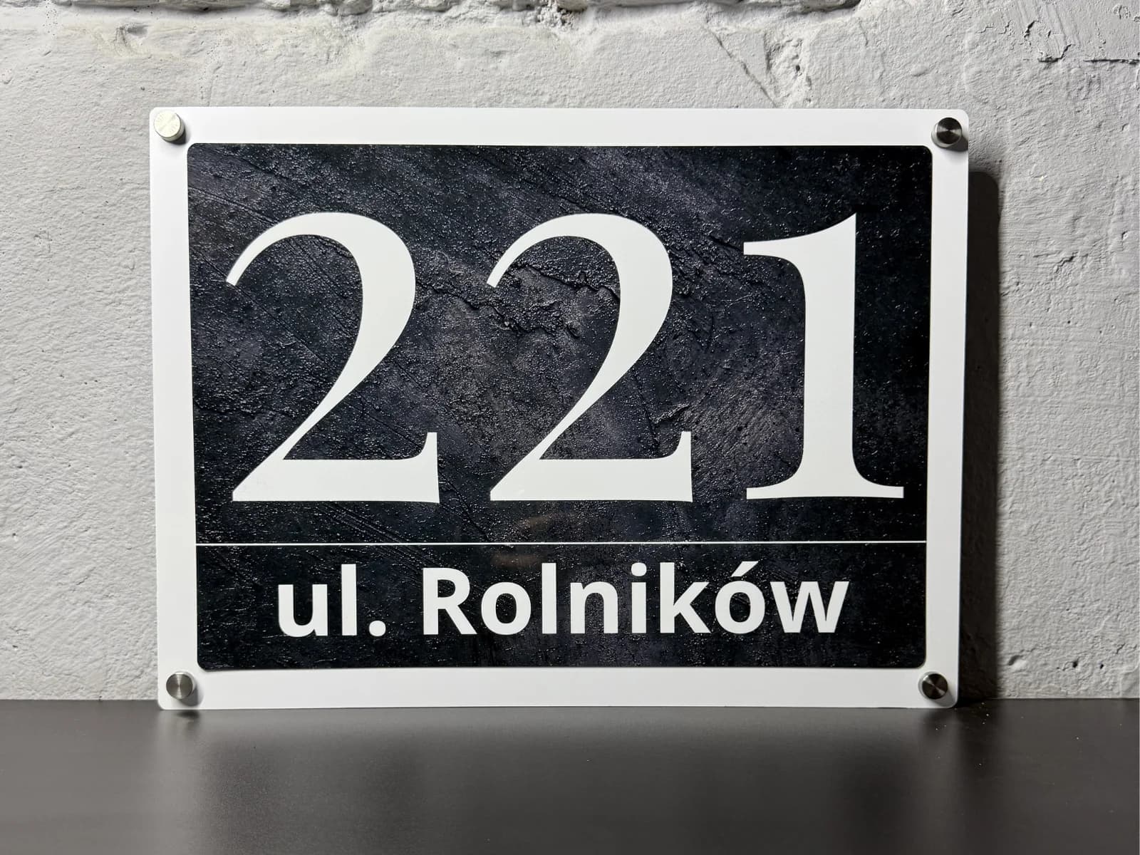 Close-up of stainless steel standoff wall-mount hardware on a classic anthracite Bolot Studio address sign showing hardware detail